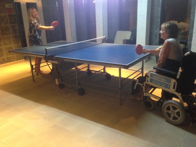 Customer using our powerchair while playing table-tennis on board cruise ship.